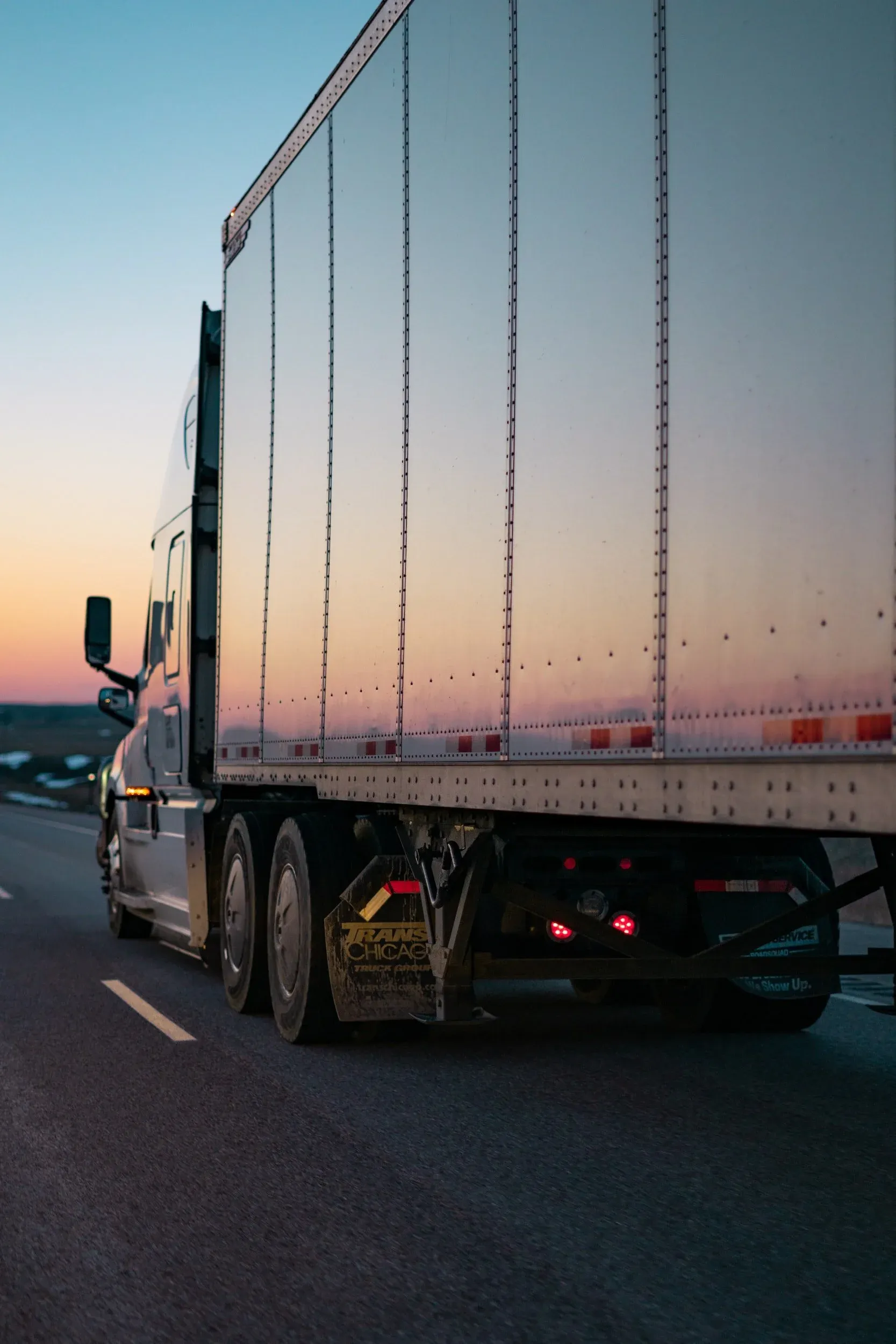 A dry van trailer on the highway at dusk.